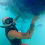 Man cleaning bottom of boat hull using a tankless dive system and scraper