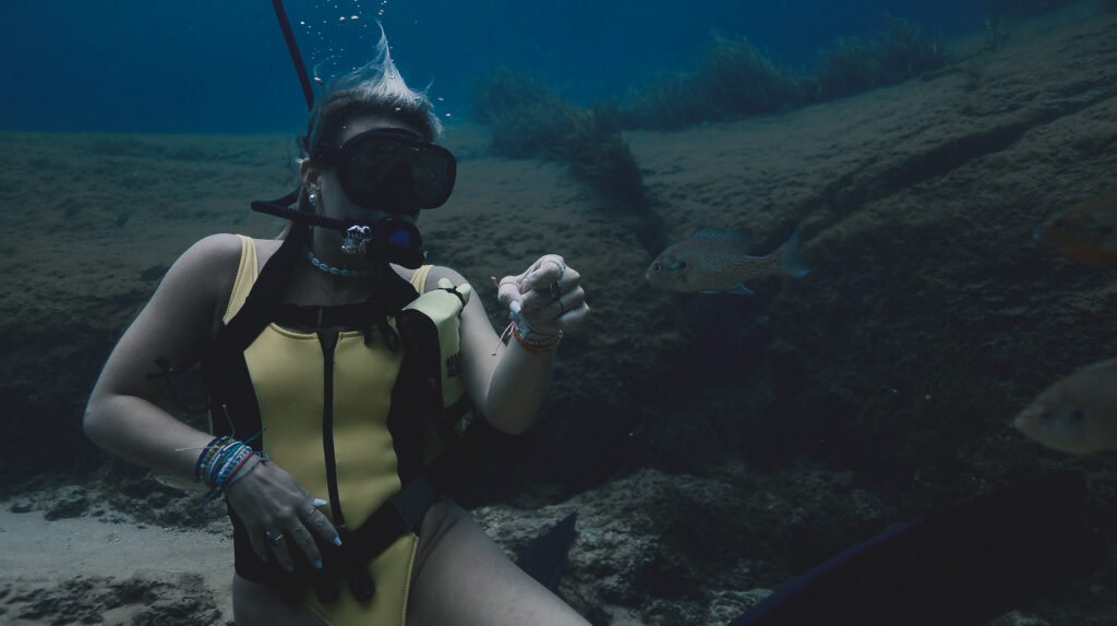 An intimate underwater encounter, as a diver from our live paddle board extends a hand to a curious fish.