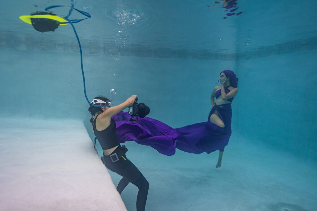 Underwater photographer with BLU3 dive system breathing apparatus, capturing a model.