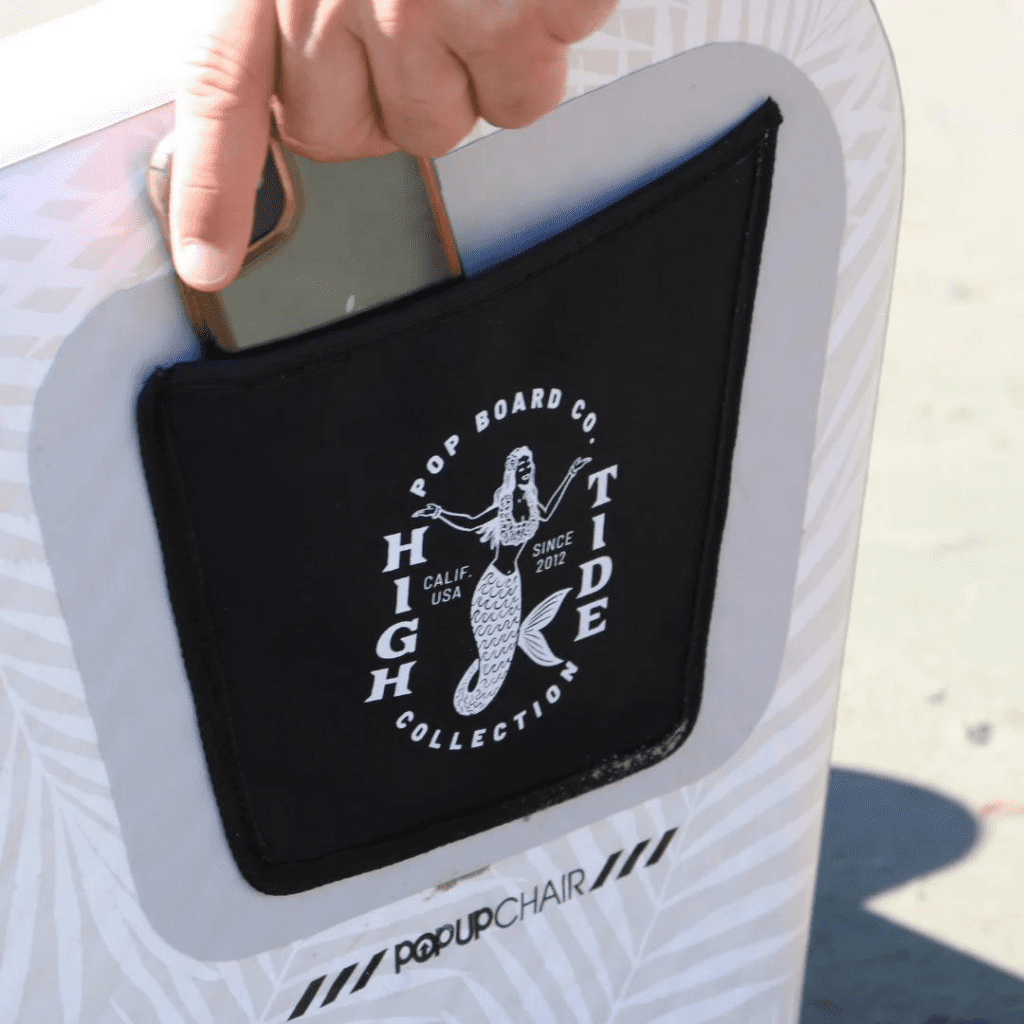 POPup-Chair-High-Tide-Collection-Pocket-1080-1080 Close-up of a hand placing an item in the pocket of a High Tide Collection POPup Chair