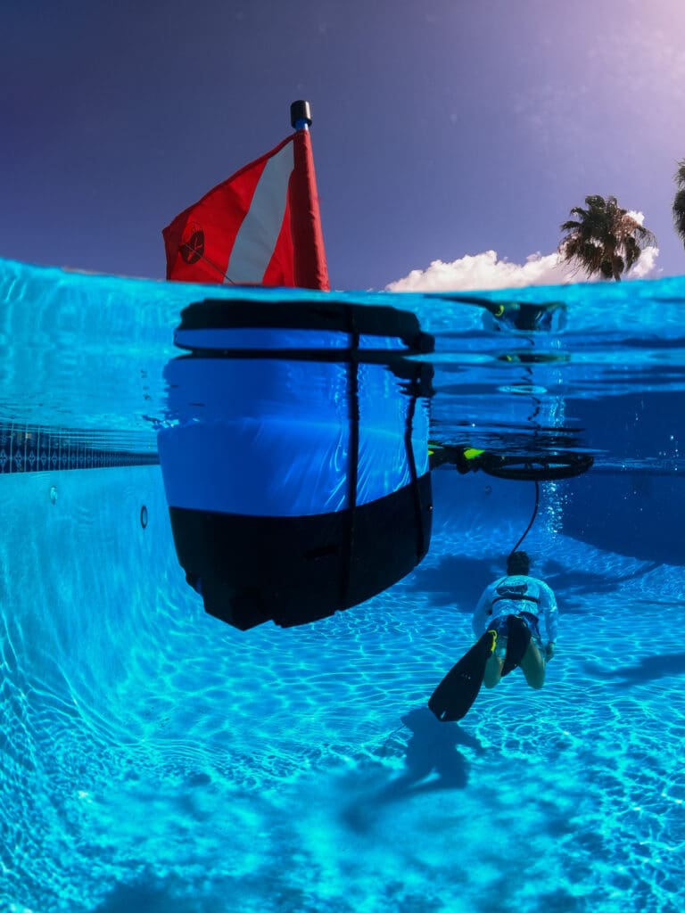 Nomad Mini floats in swimming pool with diver below.