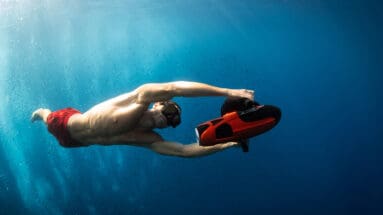 Man using Sublue Vapor underwater scooter while snorkeling in clear blue ocean