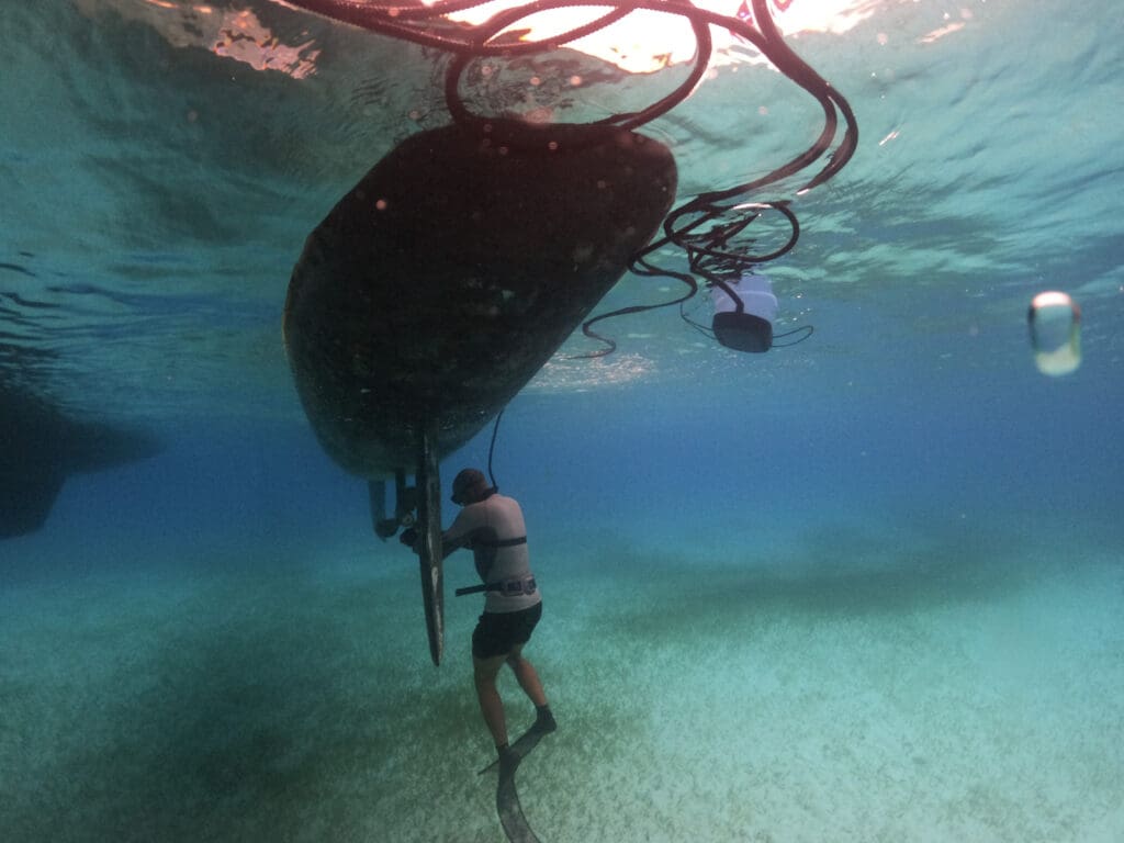 Diver using a BLU3 Nomad portable surface supplied diving system to inspect and clean the propeller of a boat underwater.