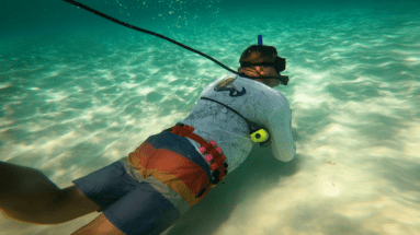 Diver exploring shallow water around his boat using a tankless dive system