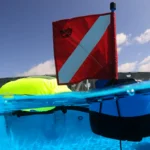 A bright red dive flag floats above water, with a buoy visible below